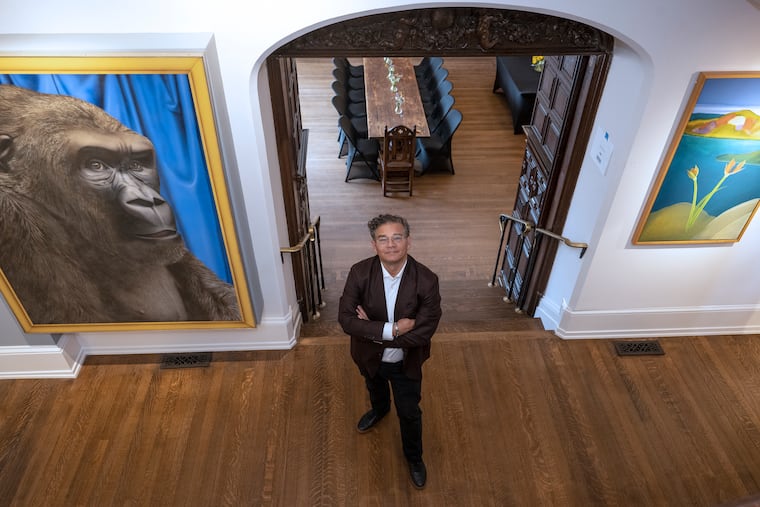 William R. Valerio standing in front of the entrance the Frances M. Maguire Hall's first floor dining room under flanked by (left) Tom Palmore's 1975 painting "Bamboo" and (right) Elizabeth Osborne, By the Deep Blue Sea, 1989-90, Acrylic on canvas.