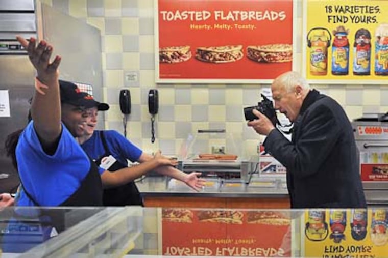 At the first ever Wawa store that opened in 1964 on MacDade Boulevard in Folsom, Don Price (right) takes photos of employees Lakisha Staten (left) and Cera Davis. Wawa is marking its 45th anniversary. (Sharon Gekoski-Kimmel / Staff Photographer)