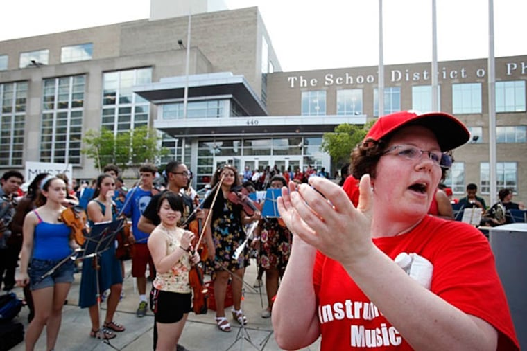 File photo: Margaret Lineman, an instrumental music teacher, applauds a group of high school music students after they played at a rally outside the School District of Philadelphia headquarters before a May public meeting by the School Reform Commission and a vote on the budget. (MICHAEL S. WIRTZ / STAFF)
