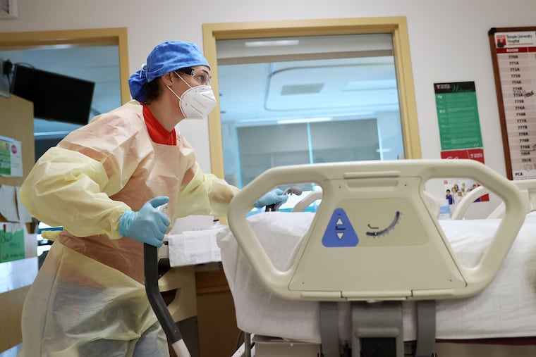 Nurse Felicia Nemick wheels an empty bed out of a room before moving another patient into it in a COVID-19 intensive care unit at Temple University Hospital's Boyer Pavilion last year.