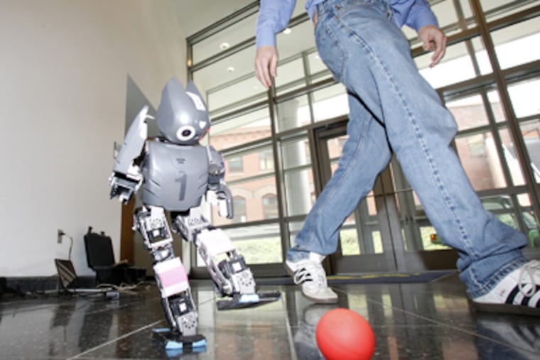 A humanoid soccer robot kicks a ball at the Philly Robotics Expo. Teams from Philly-area high schools joined in the event at Drexel University. YONG KIM / Staff Photographer