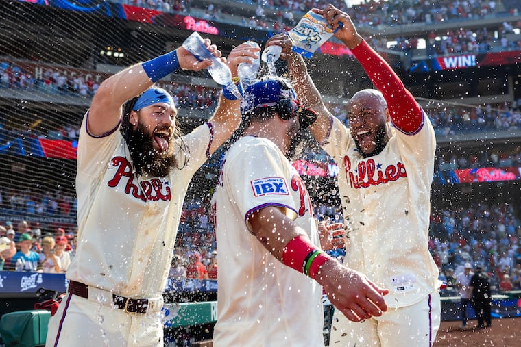 Brandon Marsh and Bryan De La Cruz douse Kyle Schwarber after his game-winning home run on Sunday.