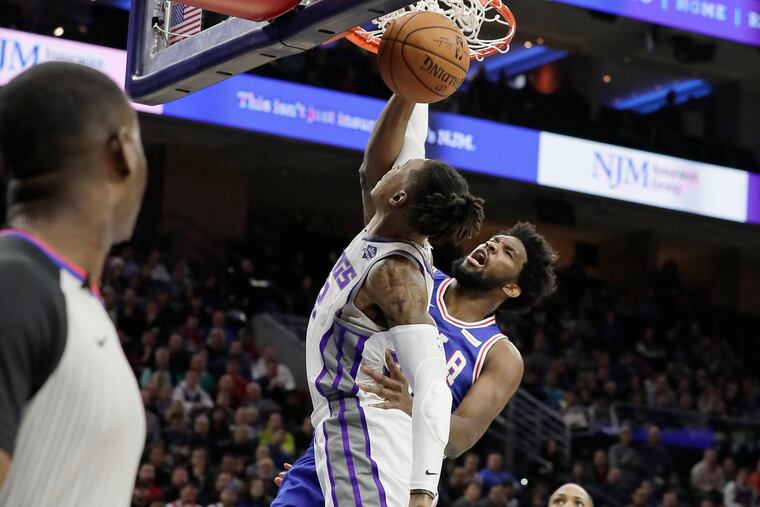 Sixers center Joel Embiid dunks over former teammate Richaun Holmes.