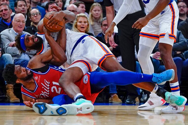 Joel Embiid (21) fights for control of the ball with New York Knicks' Mitchell Robinson (23) during the first half of Tuesday's game at Madison Square Garden.