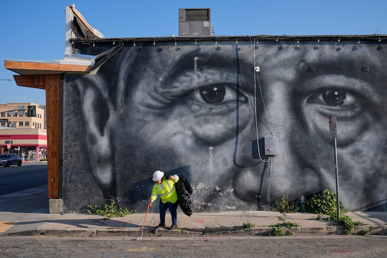 A sanitation worker picks up trash next to a mural of César Chavez in Bakersfield, Calif., Thursday.