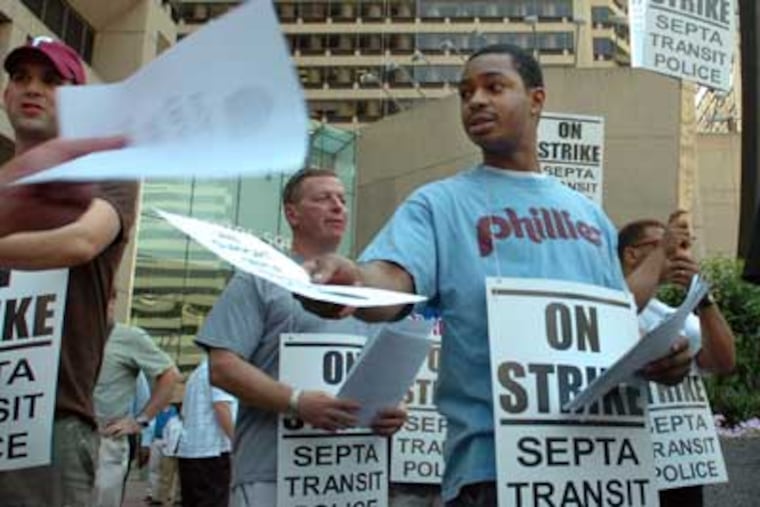 Omari Bervine, center, of New Jersey hands out flyers in front of the 15th and Market SEPTA station during the transit officers' strike.