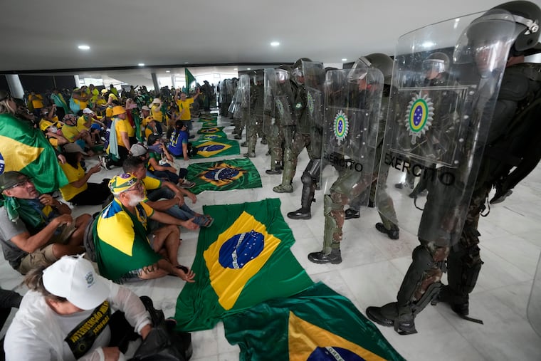 Protesters, supporters of Brazil's former President Jair Bolsonaro, sit in front of police inside Planalto Palace after storming it, in Brasilia, Brazil, Sunday, Jan. 8, 2023. Planalto is the official workplace of the president of Brazil.