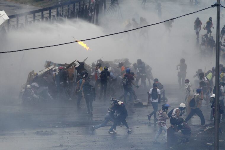 Demonstrators clashing with authorities on the fence of an air base in Caracas, Venezuela, in June.