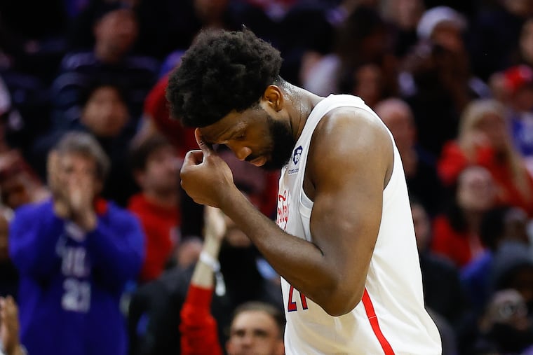 Sixers Joel Embiid wipes his head.