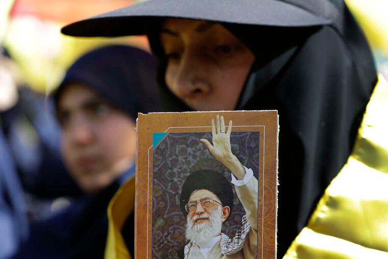 Listening to Nasrallah's speech , which was broadcast at the Mashghara rally, a woman holds a picture of Iran's Ayatollah Ali Khamanei. HUSSEIN MALLA / Associated Press