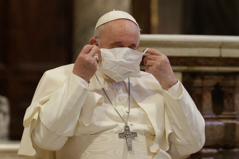 Pope Francis putting on a face mask before an event in Rome on Oct. 20.