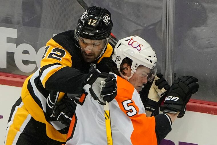 Pittsburgh's Zach Aston-Reese (12) checks the Flyers' Phil Myers (5) during the first period Tuesday. Aston-Reese was given a tripping penalty on the play.