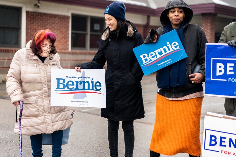 A New Hampshire voter is offered a Bernie Sanders campaign sign after casting her vote at a polling location in Nashua, N.H., on Tuesday.