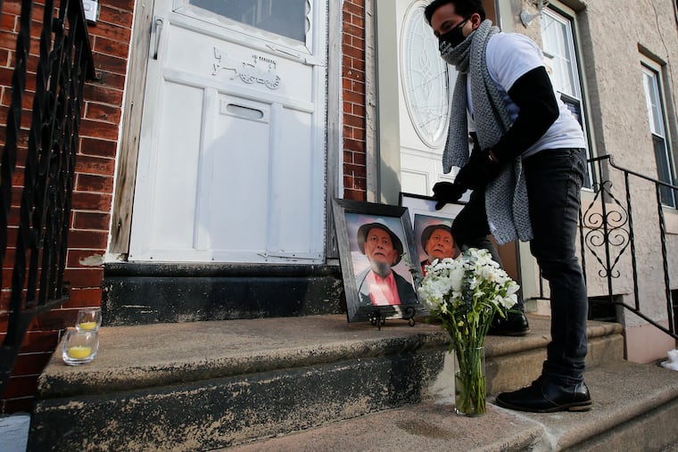 Geo Gesmundo places portraits of his 83-year-old father, Mauricio Gesmundo Sr., before a vigil at their North Philadelphia home on Feb. 6, 2021.