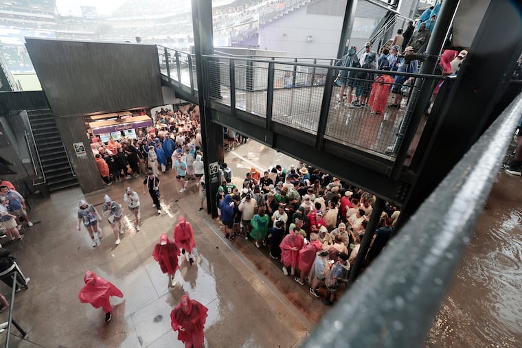 Fans take cover from the pouring rain during halftime of Monday's World Cup game between France and Iraq inside Philadelphia Stadium.