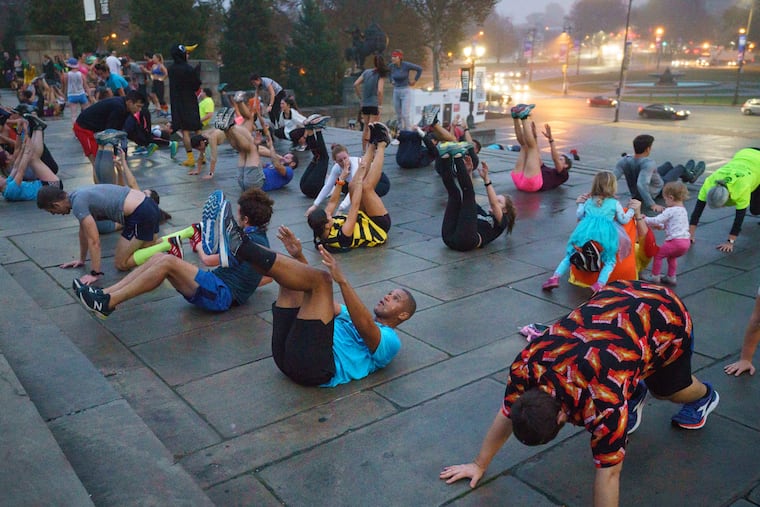 Howard Monroe, turquoise shirt and black shorts front center doing sit up, and Matt Baumann, orange shirt front right doing a push up, participate in the November Project, a free workout, on the steps of the Philadelphia Art Museum, in Philadelphia, October 30,2019.