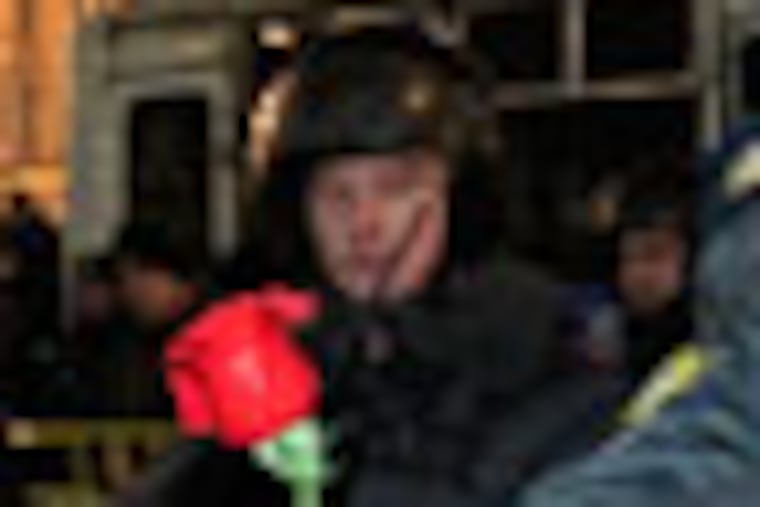 A woman tries to present a scarlet rose to a police officer during protests against alleged vote rigging in Russia's parliamentary elections in Triumphal Square in Moscow, Russia, Wednesday, Dec. 7, 2011. Protesters energized by the declining electoral fortunes of Russia's ruling party try for a third straight night of demonstrations in Moscow, facing off against a heavy police contingent.(AP Photo/Ivan Sekretarev)