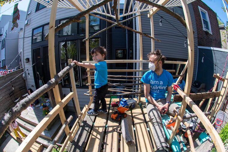 Architect Alex Gilliam and his 3-year-old son, Scout, enjoy the sunshine on the treehouse that Gilliam constructed on the fence separating his Brewerytown rowhouse and a neighbor's house.