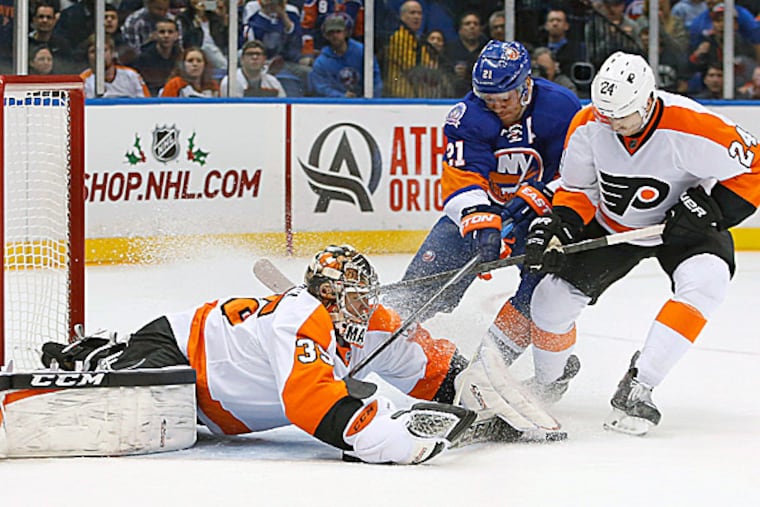 Islanders right wing Kyle Okposo and Flyers right wing Matt Read battle for control of the puck in front of goalie Steve Mason in the second period. (Kathy Willens/AP)