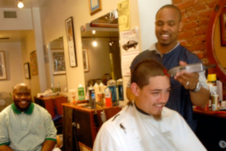 Steve White , cutting hair at his Classic Barber & Beauty Salon, said the area is "much better." Chris Brock (left) works at the shop.