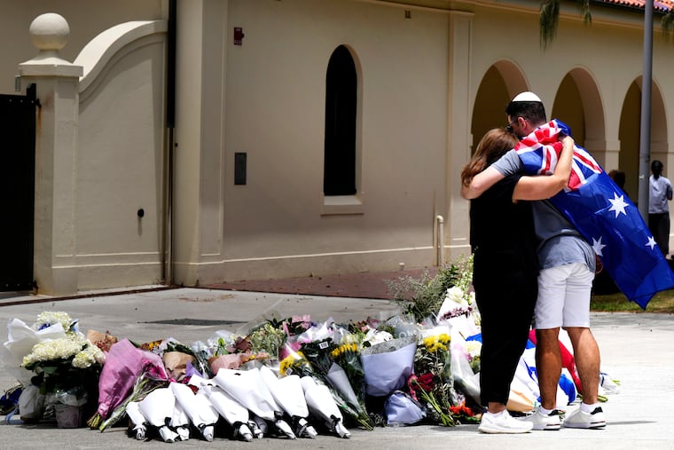A couple lay flowers at a tribute to shooting victims outside the Bondi Pavilion at Sydney's Bondi Beach, Monday, Dec. 15, 2025, a day after a shooting there killed at least 15.
