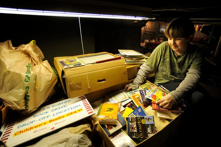 Dakota Williams sorts books. “I feel good,” he said. “I thought it just would be 200 books and $100, and that would be it, but obviously not.” (TOM GRALISH / Staff Photographer)