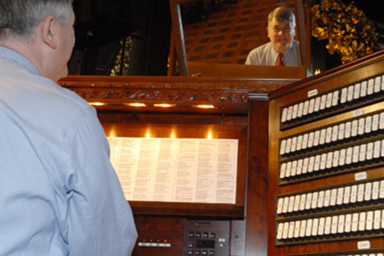 Marc Cheban is reflected in the mirror above the 55-ton pipe organ as he plays for yesterday's caroling session at Longwood. (Bob Williams / For the Inquirer)