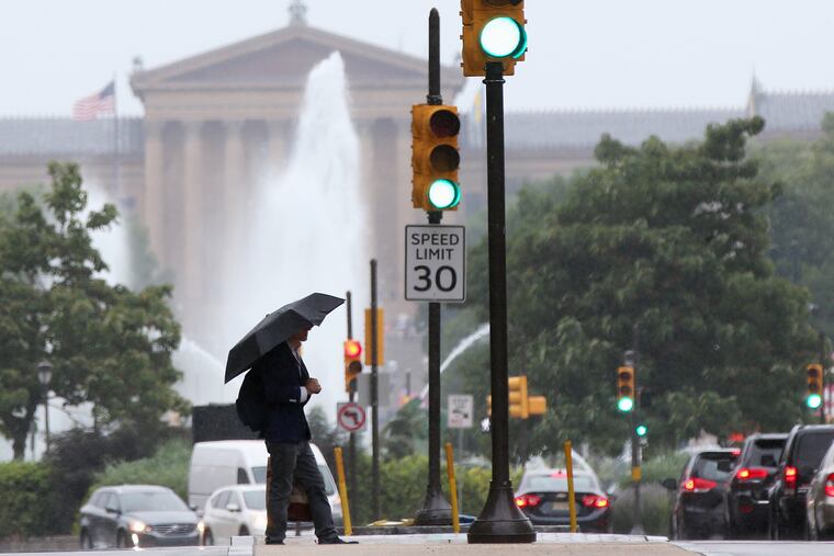 A man carries an umbrella while crossing the Benjamin Franklin Parkway in Center City during the weekend. It keeps on raining. TIM TAI / Staff Photographer