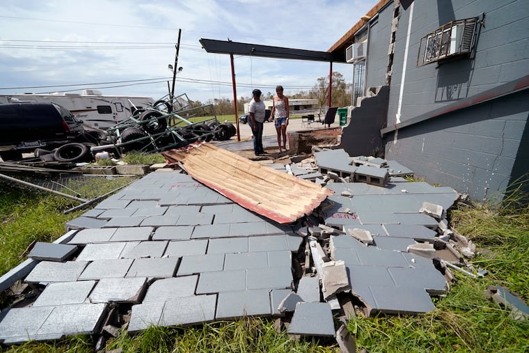 Monique Benjamin (left) and her daughter Amiah Winbush, 17, look at the damage to their car detailing business, in Lake Charles, La., in the aftermath of Hurricane Laura on Sunday. Two new storms have formed in the Atlantic Basin.