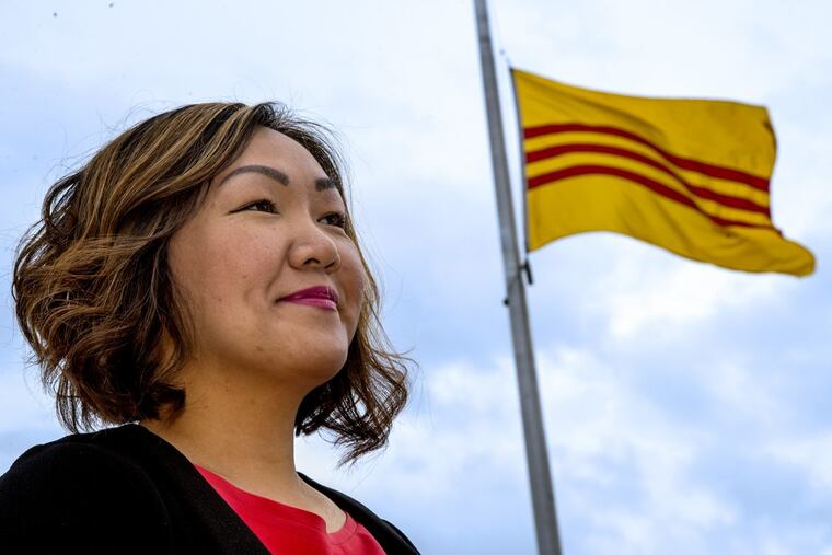 Michelle U. Quach stands under a South Vietnamese flag in South Philadelphia.