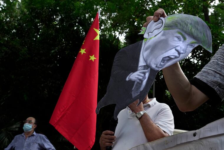 In this Aug. 8, 2020, file photo, pro-China supporters display a picture of U.S. President Donald Trump during a protest against the U.S. sanctions outside the U.S. Consulate in Hong Kong.