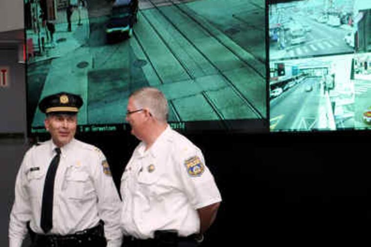 Capt. Lou Campione (left) and Lt. Tom Woltemate stand in front of the main surveillance-video screen in the Police Department's monitoring room. Police and business owners are anxious for cameras like the one at left to become operational.