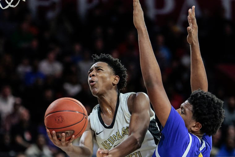 Neumann Goretti’s Robert Wright III goes up between West Catholic’s Marcus Branker Jr., left, and Zion Stanford, right.