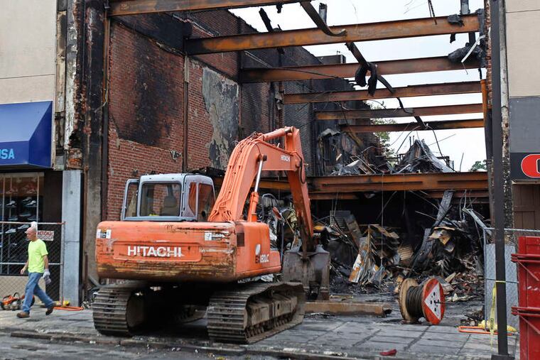 MICHAEL BRYANT / STAFF PHOTOGRAPHER Debris is cleared from the burned-out shell of the Payless store on 69th Street in Upper Darby.