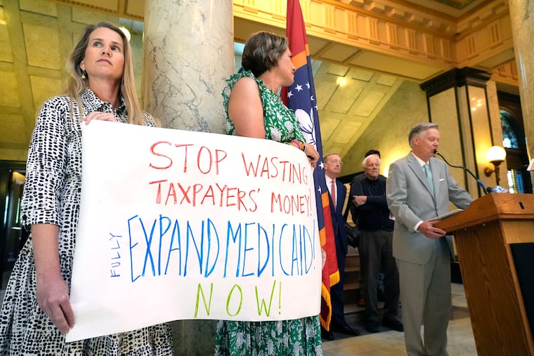 Demonstrators hold a sign urging lawmakers to fully fund a Mississippi Medicaid expansion plan at the state Capitol in Jackson, Miss., in April 2024. In Pennsylvania, working people are concerned about the possibility of significant cuts to Medicaid, former Gov. Tom Corbett writes.