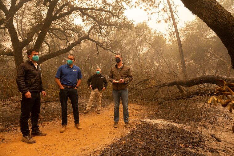 California Gov. Gavin Newsom, right, takes notes as he tours the North Complex Fire zone with California Secretary for Environmental Protection Jared Blumenfeld, left, and California Secretary for Natural Resources Wade Crowfoot, second left, in Butte County on Friday, Sept. 11, 2020, outside of Oroville, Calif. Newsom toured the fire-ravaged region Friday and strongly asserted that climate change was evident and pledged to redouble efforts to “decarbonize” the economy.