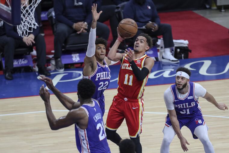 Trae Young shoots over Sixers Joel Embiid, Matisse Thybulle and Seth Curry during the fourth quarter during Game 5.