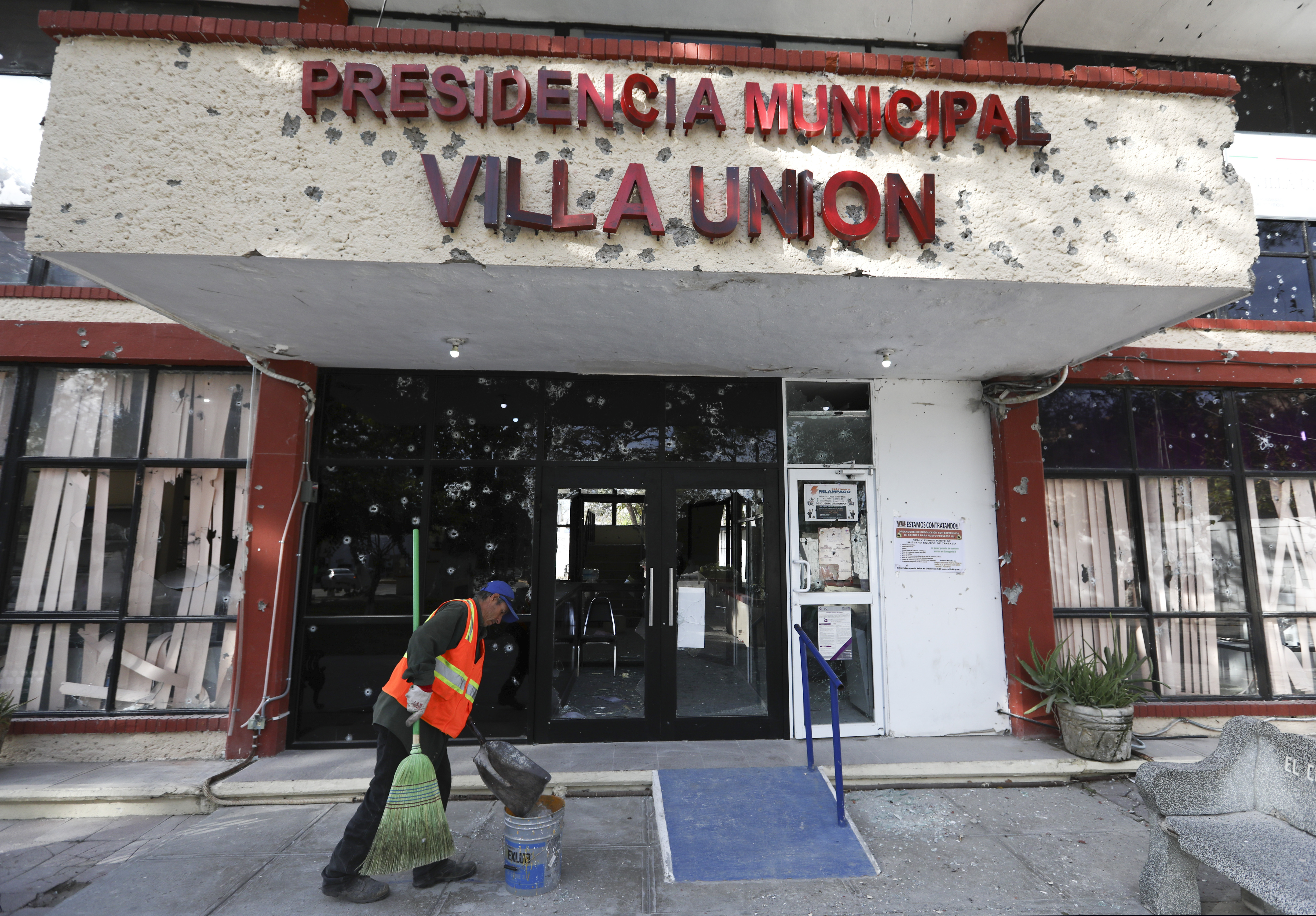 A worker cleans up outside City Hall, riddled with bullet holes, in Villa Union, Mexico on Monday.