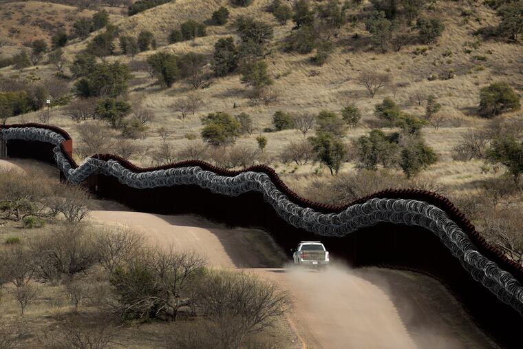 A Customs and Border Control agent patrols on the US side of a razor-wire-covered border wall along the Mexico east of Nogales, Ariz.