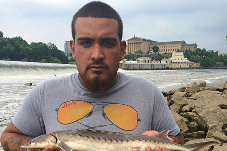 Cell phone photo of an unknown angler and the shortnose sturgeon he caught in the Schuylkill River just below the Fairmount Dam. (Pennsylvania Fish & Boat Commission)