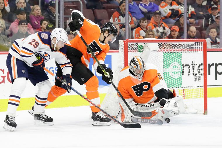 Flyers rookie goaltender Carter Hart getting ready to cover the puck with defenseman Travis Sanheim against Edmonton on Saturday. The Flyers won their seventh straight, 5-4, in overtime. Hart has won six in a row.