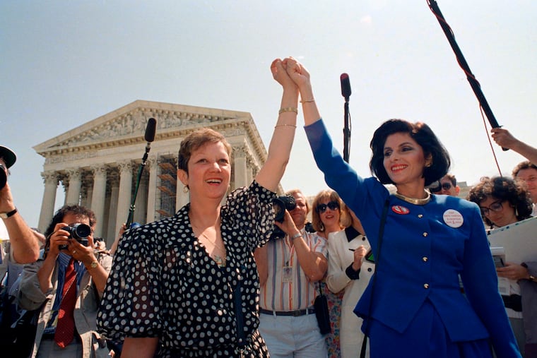 Norma McCorvey, also known as Jane Roe in the 1973 court case, left, and her attorney Gloria Allred hold hands as they leave the Supreme Court building in Washington after sitting in while the court listened to arguments in a Missouri abortion case, on April 26, 1989.