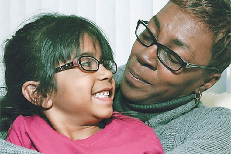 Michelle Roberts-Edwards snuggles her precocious adoptive child, Cristina, 6, who got a heart transplant before moving in with her new mom. (Steven M. Falk / Staff Photographer)