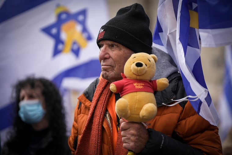 A man holds a teddy bear at the so-called "Hostages Square" in Tel Aviv, Israel, on Thursday, Feb. 20, 2025, after the bodies of four Israeli hostages were handed over by Palestinian militant groups to the Red Cross in Gaza.