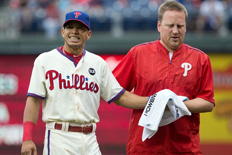 Philadelphia Phillies second baseman Cesar Hernandez (16) is helped off the field by a trainer after being injured in a collision with Chicago Cubs first baseman Anthony Rizzo (44) during the seventh inning at Citizens Bank Park. The Phillies won 7-4.