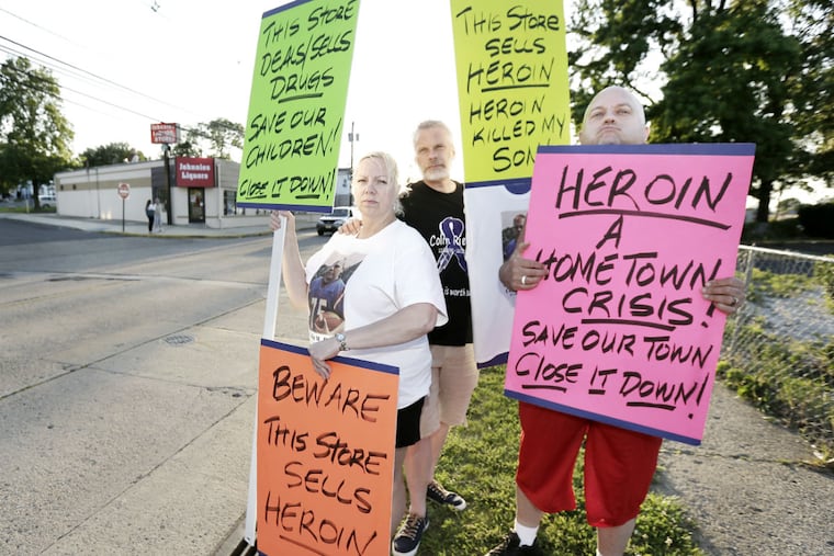 Bobbie Lynn Riebel, husband Don Reibel and Craig Leadbeater (all of Bellmawr) stand with their signs in front a laundromat and across the street from Johnnies Liquors on W. Browning Rd. in Bellmawr on June 9, 2016. Two weeks ago there was a large drug bust at Johnnies and the Laundromat across the street. Since then, town residents have been protesting periodically outside the store, calling for it to be closed down.