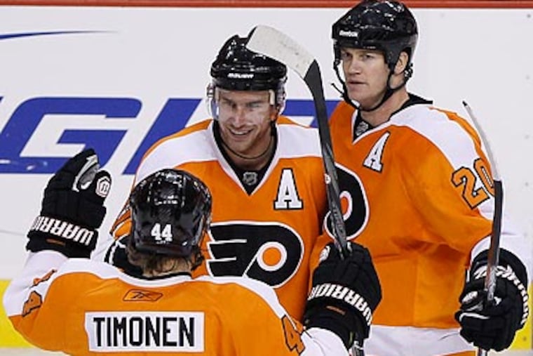 Jeff Carter, Kimmo Timonen and Chris Pronger celebrate Carter's empty-net goal. (Matt Slocum/AP)