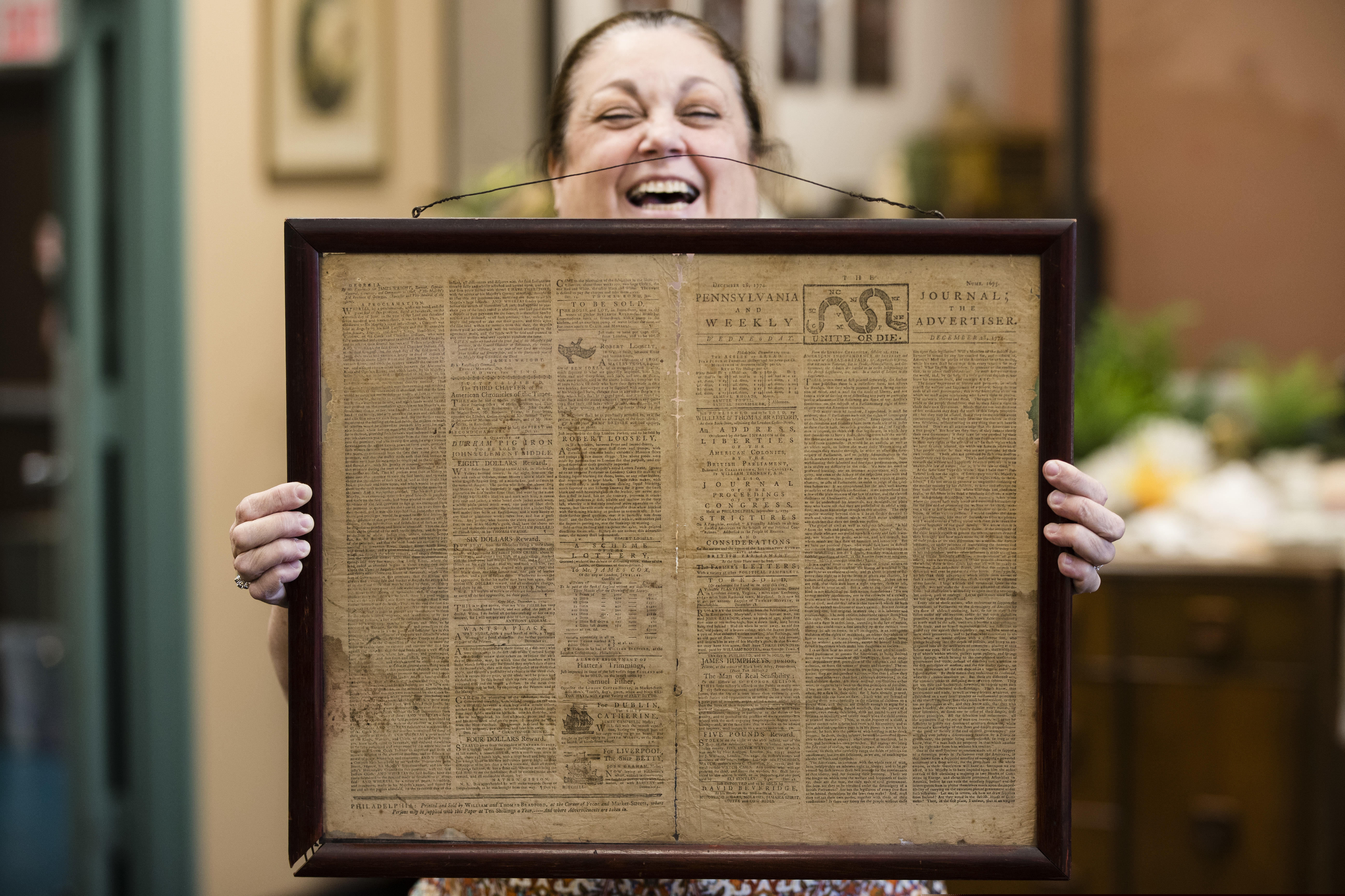 FILE - In this Thursday, Oct. 25, 2018 file photo, Heather Randall displays a Dec. 28, 1774 Pennsylvania Journal and the Weekly Advertiser at the Goodwill Industries South Jersey in Bellmawr, N.J. An original 1774 Philadelphia newspaper that was discovered at a New Jersey Goodwill is heading to a Philadelphia philosophy society founded by Benjamin Franklin.