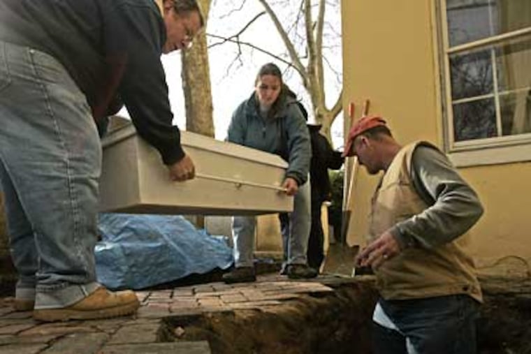Joe Tursi (left) and Kimberly Morrell carry a casket with the remains of the Rev. Stephen Gloucester, his wife Ann and David Winrow, while archaeologist Douglas Mooney waits in the grave site at the Old Pine Cemetery. ( Michael Perez / Staff Photographer )