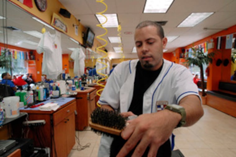 Elvin Gonzalez cuts hair in his barbershop at Tioga Street and Kensington Avenue. He likes the lower cost of living here.